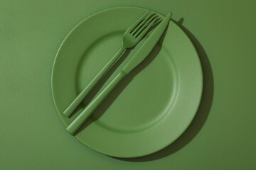 Fork and knife on the plate. All painted in green. Background painted in the same green color.