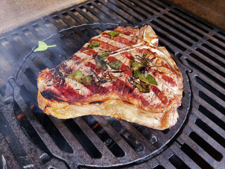 T-bone steak flavored with herbs cooks on the grill