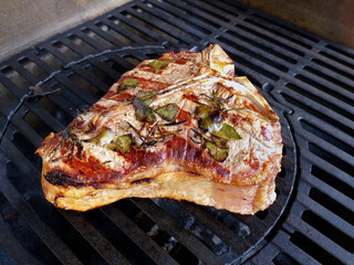 T-bone steak flavored with herbs cooks on the grill