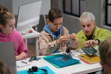 Kids with teacher working together on project with electric toys and robots at robotics classroom