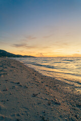 Sandy beach, surf and coastline at colorful sunset
