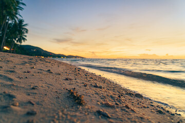 Sandy beach, surf and coastline at colorful sunset