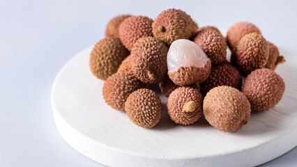 Several Ripe Organic Litchi Fruits on a Wooden Tray Copy Space Blue Background