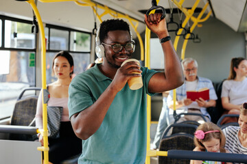 African American man drinking coffee and listening music in bus