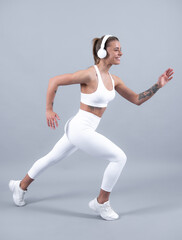 Fitness woman runner. Beautiful strong happy cheerful sports woman posing on isolated background. Happy young woman in sports clothing smiling. Muscular fitness model.