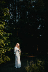 Fototapeta premium blonde woman with long hair in a dress walks through the forest, the concept of the beginning of summer.