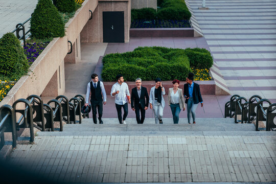 Group of happy business people walking together upstairs
