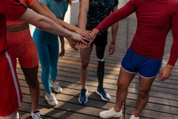 Group of runners stacking hands while standing outdoors