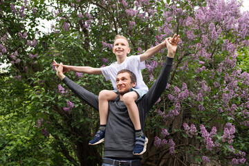 Naklejka na ściany i meble Dad picked up and put a cute child on his shoulders. Son flies like a plane