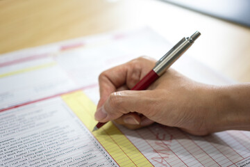 Action of safety officer is using a pen to marking checklist in work permit document form. Safety...