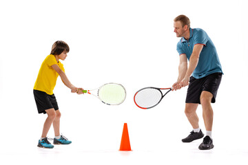 Male tennis player, coach training with teen to play tennis isolated over white studio background. Concept of sport, achievements, hobby, skills