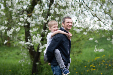 Naklejka na ściany i meble The boy is sitting on Dad's back and they are laughing