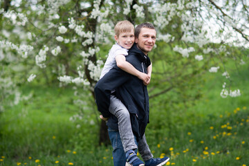 Naklejka na ściany i meble The boy is sitting on Dad's back and they are laughing