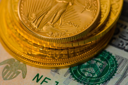 Closeup image of a stack of gold coins photographed on top of a United Stated Dollar bill. Higher saturation
