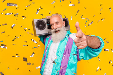 Photo of positive excited aged man carry boom box point finger camera you isolated on yellow color...