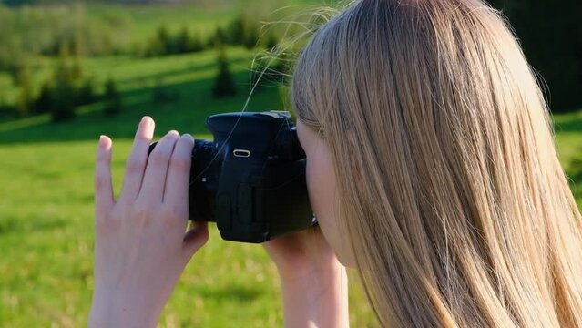 Close-up of a fair-haired girl who takes pictures of nature on a summer day.