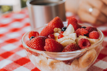 Healthy organic raw child diet eco friendly food.Bright colorful Red checked tablecloth.raspberry, strawberry, black currant, coffee cup. family having fresh summer morning breakfast picnic 