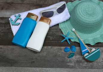 Komposition Sonnenschutz: Flaschen mit Sonnencreme, Sonnenbrille und Hut.