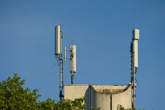 Antenna mast for mobile radio communications mounted at a roof top in front of blue sky 
