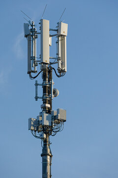 close-up of an antenna mast for mobile radio communications mounted at a roof top in front of blue sky 