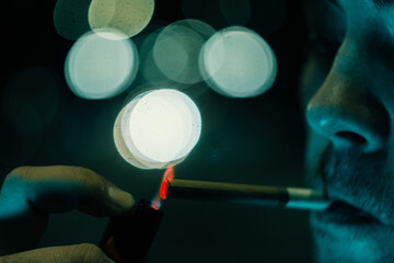 man lights a cigarette, photo at night