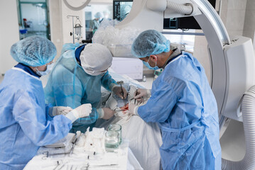 Doctors in the operating room perform a heart operation to introduce a pacemaker. The doctor in the operating room spreads the incision with clamps. Doctors perform heart surgery with the utmost care - obrazy, fototapety, plakaty