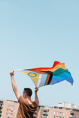 waves a progress pride flag above his head - obrazy, fototapety, plakaty