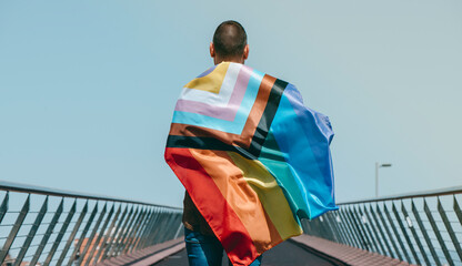 wrapped in intersex-inclusive progress pride flag - obrazy, fototapety, plakaty