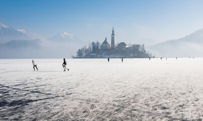 Winter morning at frozen lake Bled. Ice skating on the frozen lake. 