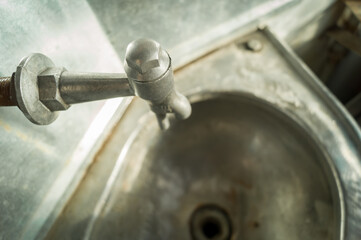 A water faucet above the sink in the old toilet of the passenger car of an electric train....