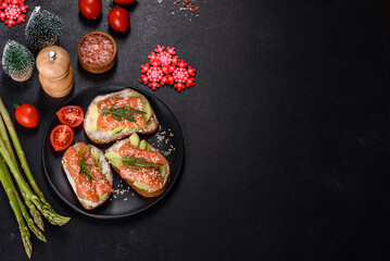 Toast sandwich with butter, avocado and salmon, decorated with arugula and sesame seeds, on a christmas table