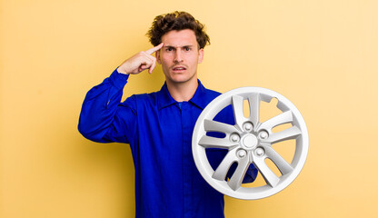 young handsome teenager feeling confused and puzzled, showing you are insane. car mechanic concept