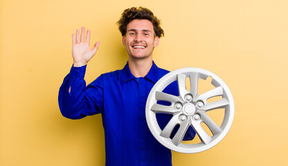 young handsome teenager smiling happily, waving hand, welcoming and greeting you. car mechanic concept © kues1