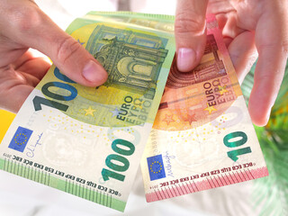 Hands hold hundred and ten euro banknotes. State aid in times of crisis to compensate for...