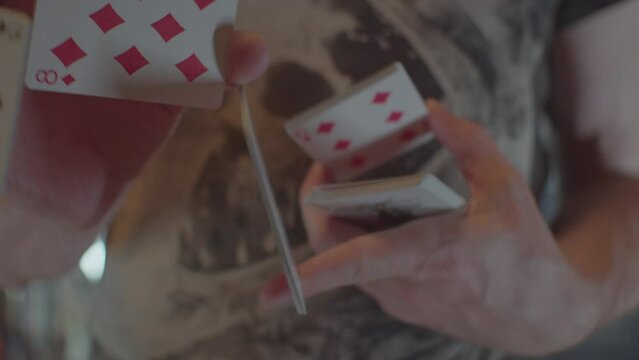 Man's hands are shuffling a deck of cards with a red back