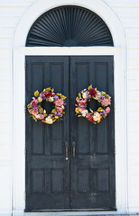 Fototapeta na wymiar two wreaths of flowers decorate village church doors 