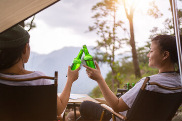 camping concept, Cheers glass bottle by camping people together at their camping site at the mountain