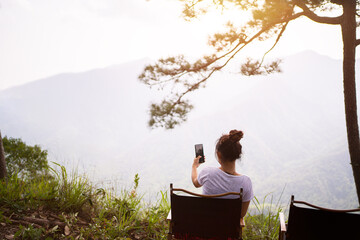 trekking concept, hiking woman use smart phone taking self photo at seaside mountain