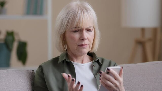 Mature Caucasian woman grandmother elderly lady with mobile phone feeling sad upset worry due to slow connection error online broken smartphone bad news puzzled with app, technology and old generation