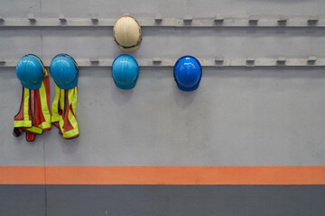 Safety helmets and worker shirt which is keep at metal rail rack at the factory wall