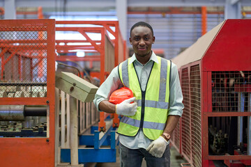 Portrait of African American engineer standing with safety helmet in metal sheet factory