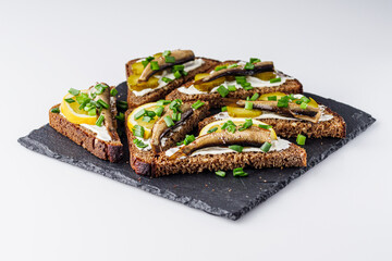 canapes with sprats on a black stone tray