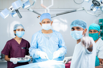 sugreon operating or doing surgery by looking monitor at operation theater with supporting staff -...