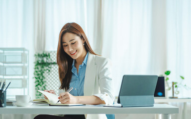 Young Asian woman sitting at a table and writing notes. Businesswoman working at her desk.