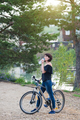 Fototapeta na wymiar Girl cyclist drinks water from bottle after a ride.