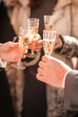 blurred festive background with glasses of champagne in people's hands and bokeh at the party. New Year's party with champagne. People hold glasses of champagne in their hands at a holiday wedding par