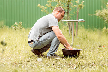 A man does his homework, cleans a cauldron in the backyard of a country house