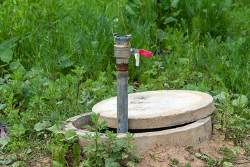 Technical concrete well with a pipe and a lever for water supply.