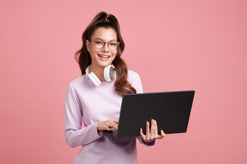Beautiful young asian women holding laptop with happy smile, standing isolated on pink background,