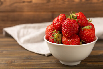 Fresh ripe strawberries in a bowl on a brown texture background.Vegetarian organic berry.Healthy food.Copy space.Place for text
